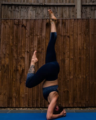 Lashara holding a supported headstand on a mat outdoors