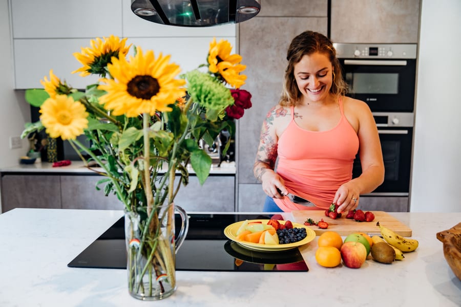 Lashara chopping strawberries in her kitchen beside a plate of fruit