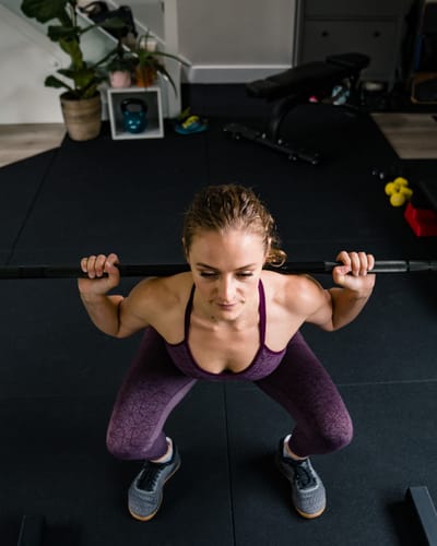 Lashara squatting with a barbell across her shoulders