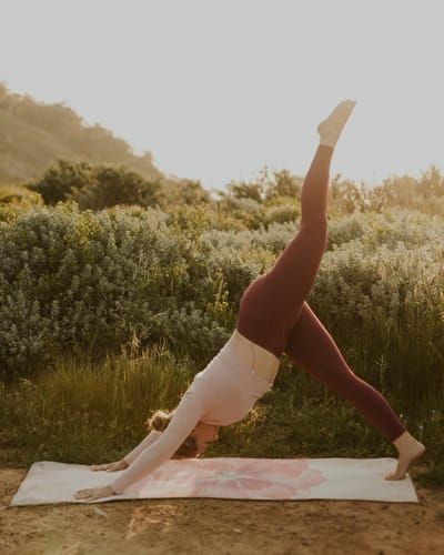 Lashara moving through a yoga flow on a mat outdoors at sunrise