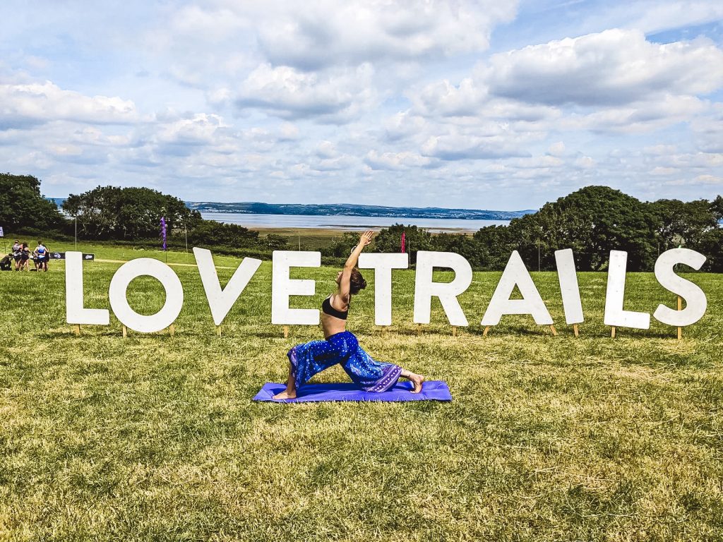 Love trails festival with girl standing in yoga pose in front of Love trails sign