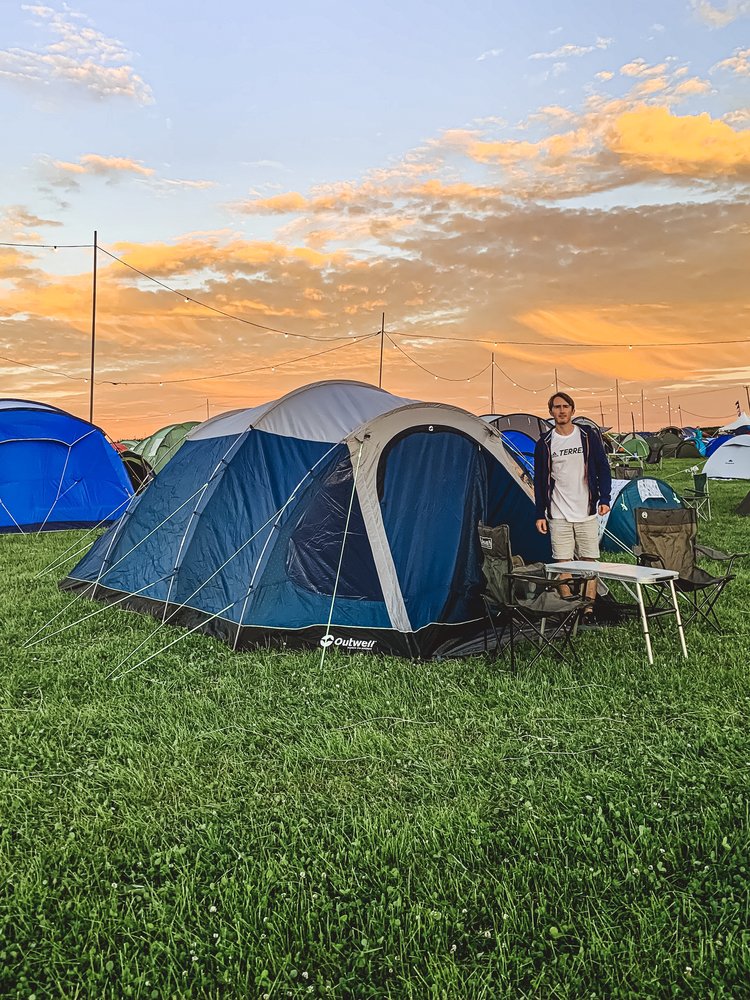 Man with tent and sunset behind